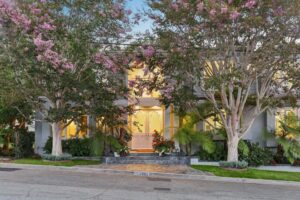 Front exterior view of 2300 John Street with pink flowering trees framing the illuminated grand entry doors.