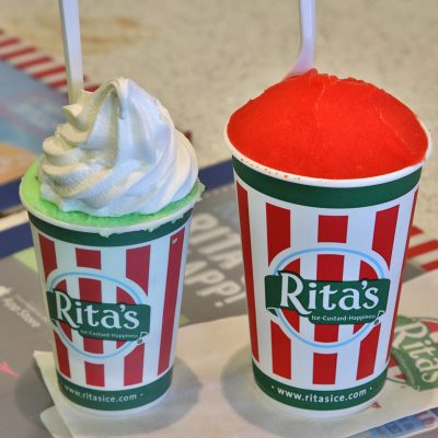 Two Rita's branded cups, one holding a green water ice with white frozen custard (galati), and the other a red water ice, illustrating the treats discussed in the article.
